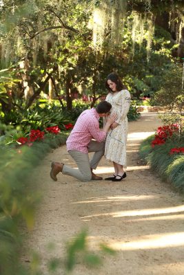 Mom-to-be in a flowing gown posing among lush greenery during a park maternity photoshoot by Katerina Krjanina.