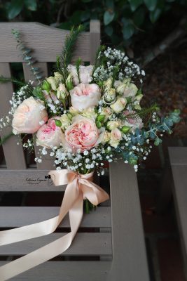 Wedding bouquet featuring ivory roses and greenery, captured against the scenic coastal gardens of Washington Oaks Gardens State Park.