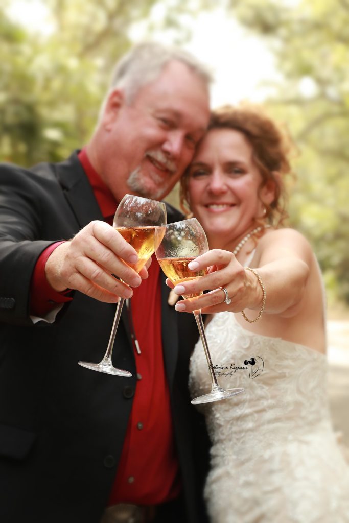 Bride and groom posing on a garden path at Washington Oaks Gardens State Park, surrounded by blooming flowers and tall trees.