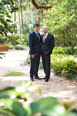 Graduate in cap and gown at Washington Oaks Gardens State Park with garden and coastal scenery.